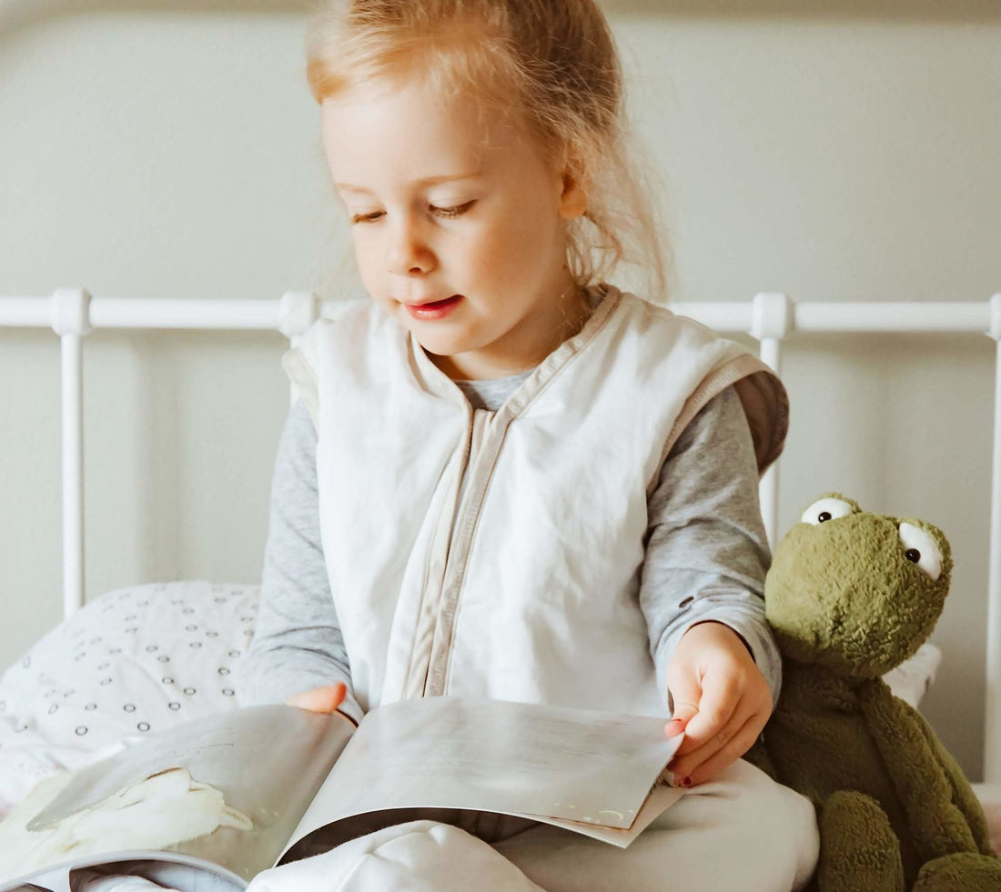 Stella reading a book in her Joey Swag baby sleeping bag